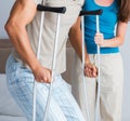 Young wife supporting husband on crutch after injury