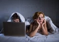 young wife upset unsatisfied and frustrated in bed while husband work on computer laptop ignoring her