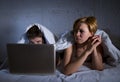 young wife upset unsatisfied and frustrated in bed while husband work on computer laptop ignoring her