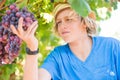 Young winemaker in straw hat examining grapes