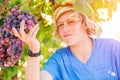 Young winemaker in straw hat examining grapes