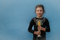 The young winner of martial arts competitions is standing with a cup in his hands. Portrait of a child with a sports award is on a