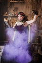 A young witch with a book in her hands cooks a potion in a large black cauldron, emitting magical purple smoke