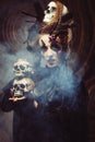 Young witch hloding skull. Bright make up and smoke- halloween theme.