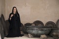 Young woman in abaya in the middle of old cooking pots Royalty Free Stock Photo