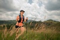 Young women active trail running across a meadow on a grassy trail high in the mountains in the afternoon with trekking pole