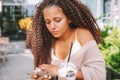 Young woman addicted to technology. Female use smartphone sitting at cafe and drinking beverage.