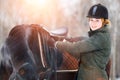 Young woman adjusting stirrups before riding horse Royalty Free Stock Photo