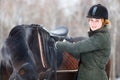 Young woman adjusting stirrups before riding horse