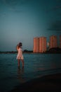 A young woman admires the city landscape. A beautiful slender happy blonde in a white summer lace dress and a straw hat Royalty Free Stock Photo