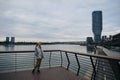 A young woman admires the views in the modern Waterfront area, near the Sava River embankment. View from the ground in a Royalty Free Stock Photo