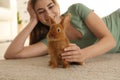 Young woman with adorable rabbit on floor. Lovely pet