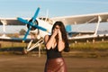 Young woman afraid to fly an airplane for traveling. Standing near the ancient airplane closes her face with her hands Royalty Free Stock Photo