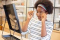 Young woman African American choosing spectacles glasses and looking mirror in optician store. Royalty Free Stock Photo