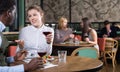 Young woman with African American colleague on friendly meeting over dinner with wine in restaurant