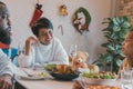 Young woman with african american husband enjoying christmas lunch of turkey at decorated home with stockings, candy Royalty Free Stock Photo