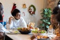 Young woman with african american husband enjoying christmas lunch of turkey at decorated home with stockings, candy Royalty Free Stock Photo