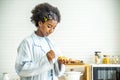 Young woman african american spreading jam on bread and eating in kitchen, student enjoys breakfast or snacks of toast with jam
