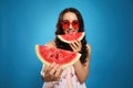 Beautiful young woman against blue background, focus on hand with watermelon
