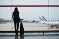 Young woman in the airport, looking through the window at planes Royalty Free Stock Photo