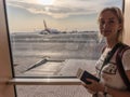 Young woman in the airport, looking through the window at planes. Royalty Free Stock Photo