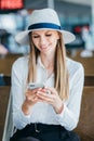 Young woman in the airport, using smartphone and drinking coffee, travel, vacations and active lifestyle concept Royalty Free Stock Photo