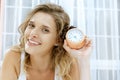 Young woman with alarmclock on the bed. Royalty Free Stock Photo