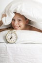 Young woman with alarmclock on the bed at morning