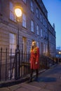 Young woman wearing long red jacket under a street light