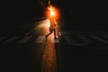 Young woman alone walking and crossing a lonely street by a pedestrian crossing at sunset Royalty Free Stock Photo