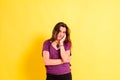 Young woman with anguished and uneasy expression  isolated on yellow studio background Royalty Free Stock Photo