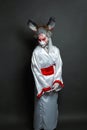 Young woman with animal makeup, mask and stage asian costume standing against black background. Halloween, carnival, performance