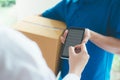 Woman signing on digital device to delivery parcel.