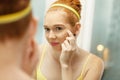 Young Woman Applies Anti-Aging Cream Looking At Mirror Royalty Free Stock Photo