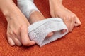 A young woman applies a fixing bandage to her leg. Close-up. Home bandage on an orange couch Royalty Free Stock Photo