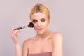 Young woman applies powder on the face using makeup brush. Beautiful girl doing contouring apply blush on cheeks. Face Royalty Free Stock Photo