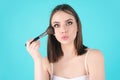 Young woman applies powder on the face using makeup brush. Beautiful girl doing contouring apply blush on cheeks. Face Royalty Free Stock Photo