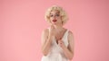 Young woman applies red lipstick on lips with makeup brush. Woman looking like Marilyn Monroe in studio on pink Royalty Free Stock Photo