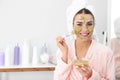 Young woman applying clay mask on her face in bathroom. Skin care Royalty Free Stock Photo