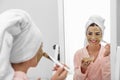 Young woman applying clay mask on her face near mirror Royalty Free Stock Photo