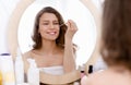 Young woman applying cosmetic serum in bathroom