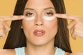 Young woman applying a creme on her low eyelids