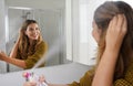 Young woman applying dry shampoo on her hair before going out. Fast and easy way to covering grey hair with instant spray dye Royalty Free Stock Photo