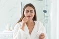 Young woman applying face cream onto her nose in bathroom Royalty Free Stock Photo