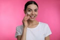 Young woman applying facial cream on pink background Royalty Free Stock Photo