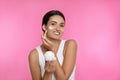 Young woman applying facial cream on pink background Royalty Free Stock Photo