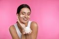 Young woman applying facial cream on pink background Royalty Free Stock Photo