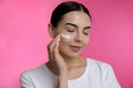 Young woman applying facial cream on pink background Royalty Free Stock Photo