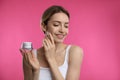 Young woman applying facial cream on pink background Royalty Free Stock Photo