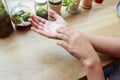 Young woman applying hands cream at wooden table.